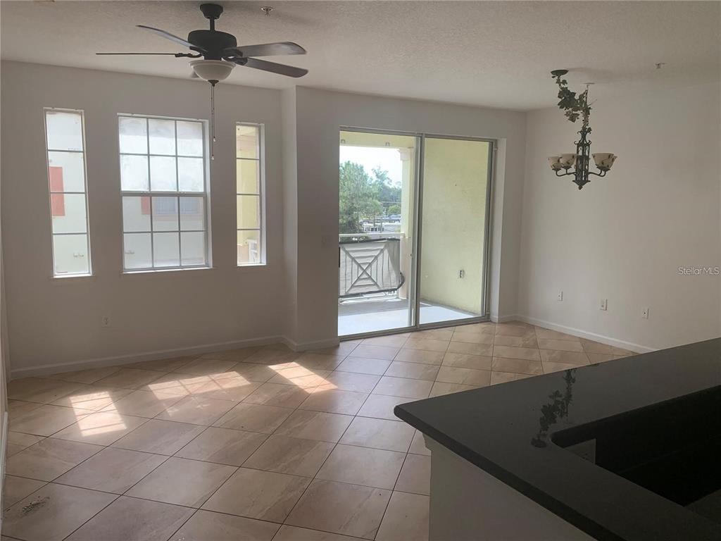 An open living area features tile flooring, a ceiling fan, and a sliding glass door — 5255 CANE ISLAND LOOP UNIT 304, KISSIMMEE, FL