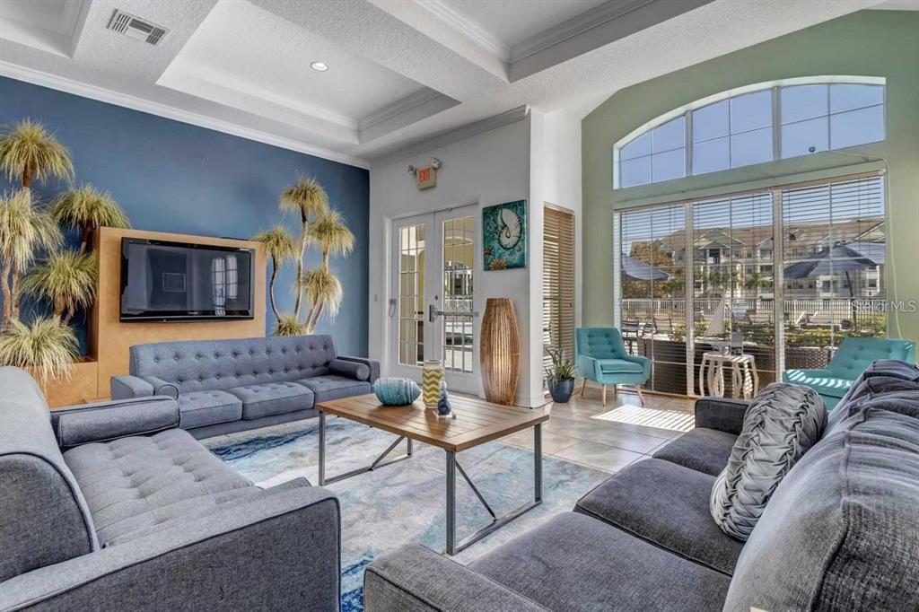 A living room features blue sofas, a wooden coffee table, and large windows overlooking a pool — 5255 CANE ISLAND LOOP UNIT 304, KISSIMMEE, FL