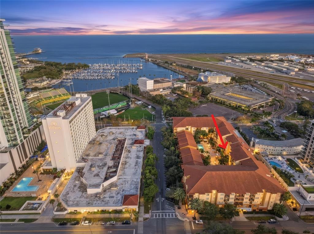 An aerial view shows a multi-story residential complex with a central courtyard near a marina — 100 4TH AVENUE S UNIT 115, ST PETERSBURG, FL