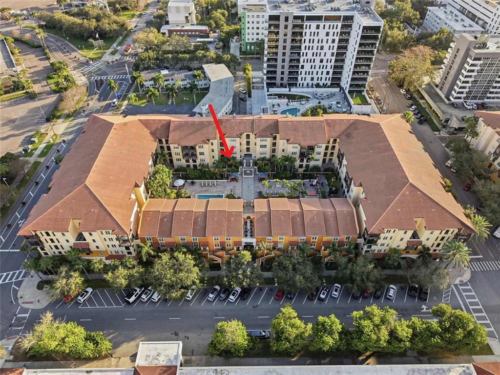 An aerial view shows a large U-shaped apartment complex with a central courtyard and pool — 100 4TH AVENUE S UNIT 115, ST PETERSBURG, FL