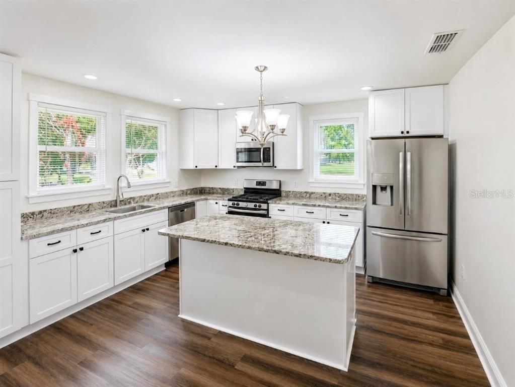 A kitchen features white cabinets, granite countertops, stainless steel appliances, and a central island — 695 LYLE PARKWAY, BARTOW, FL