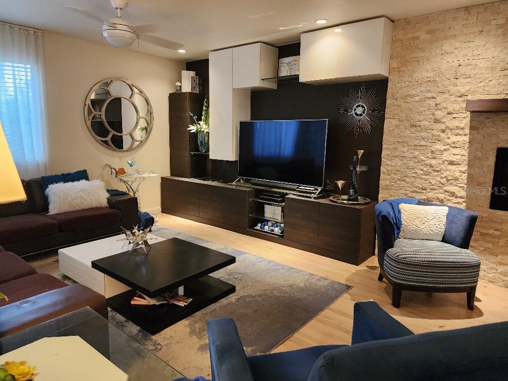 A modern living room features a large television, dark cabinetry, and a stone fireplace wall — 610 CHESTNUT OAK CIRCLE UNIT 110, ALTAMONTE SPRINGS, FL