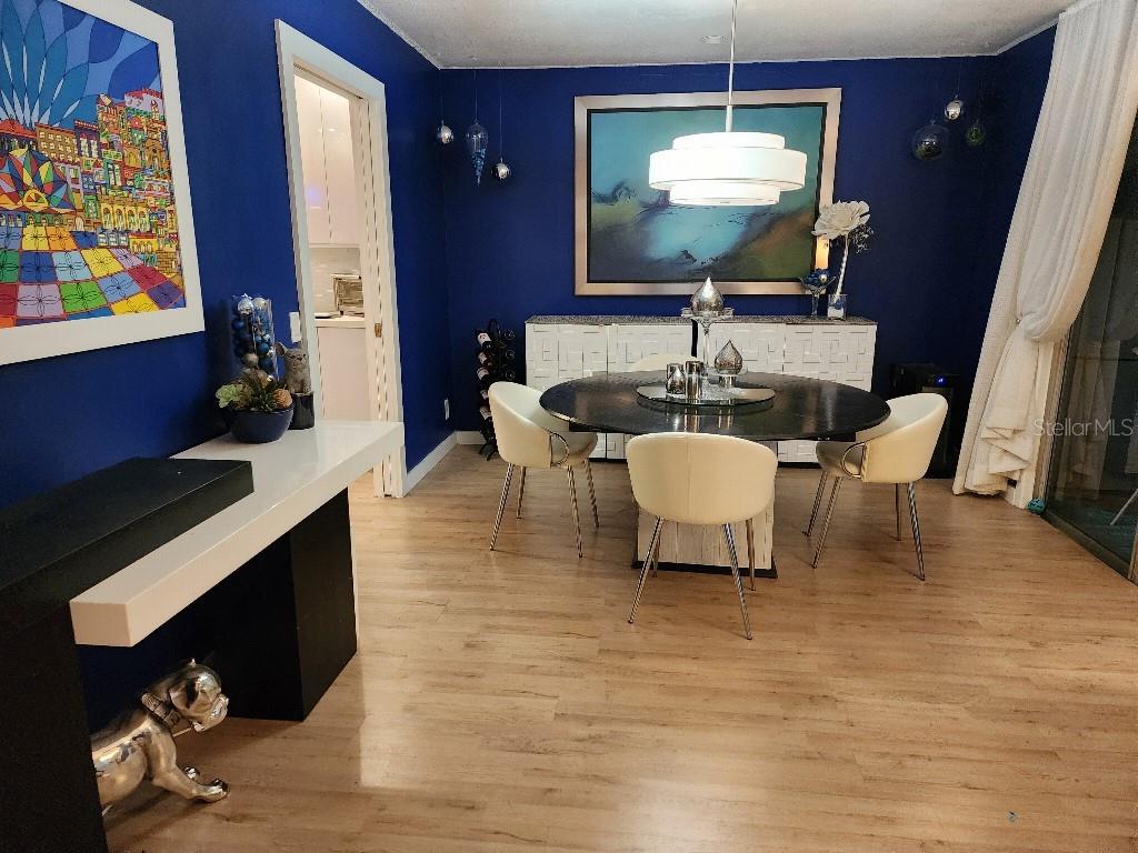 A dining room features a round black table, white chairs, and bold blue walls — 610 CHESTNUT OAK CIRCLE UNIT 110, ALTAMONTE SPRINGS, FL