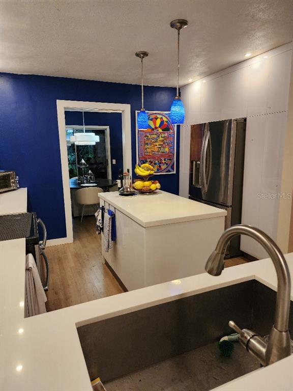 A kitchen features a white island, blue accent wall, and a stainless steel sink — 610 CHESTNUT OAK CIRCLE UNIT 110, ALTAMONTE SPRINGS, FL