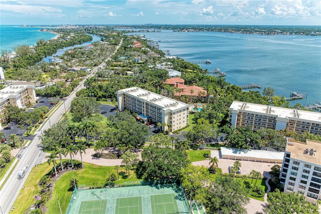 A multi-story apartment building with a parking lot and a large lawn in front — 8625 MIDNIGHT PASS ROAD UNIT 208B, SARASOTA, FL