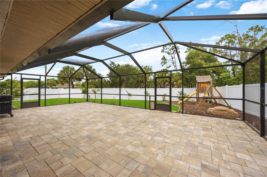 A screened-in patio features paver flooring, a metal frame, and a view of a backyard — 3691 SESAME STREET, NORTH PORT, FL