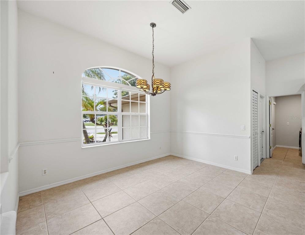 A dining room with tile floors, white walls, a chandelier, and an arched window — 3691 SESAME STREET, NORTH PORT, FL