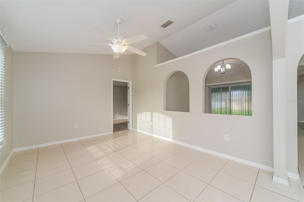A living room with light tile flooring, a ceiling fan, and two arched wall cutouts — 611 BASINGSTOKE COURT, KISSIMMEE, FL