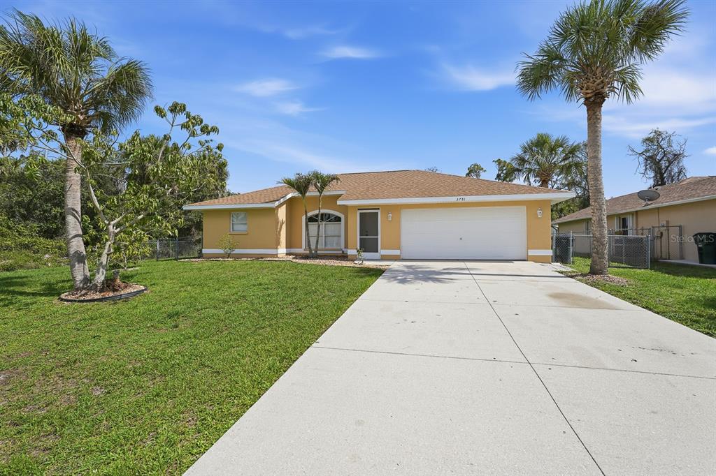 A single-story yellow house with a two-car garage and a concrete driveway — 3781 WAYWARD AVENUE, NORTH PORT, FL