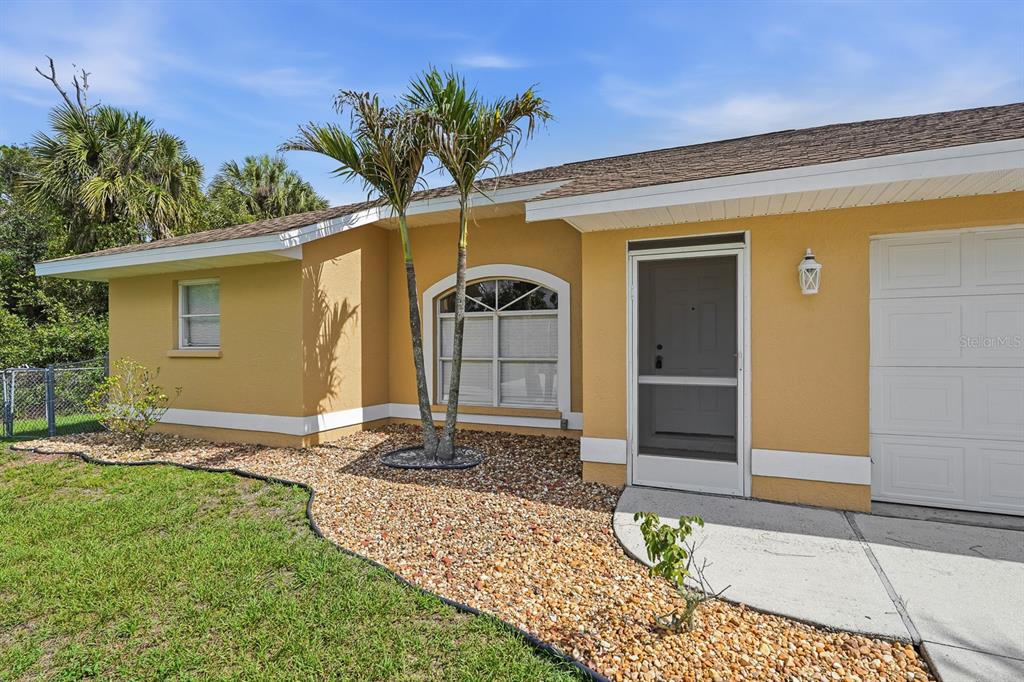 A yellow house exterior features a front door, a large arched window, and palm trees — 3781 WAYWARD AVENUE, NORTH PORT, FL