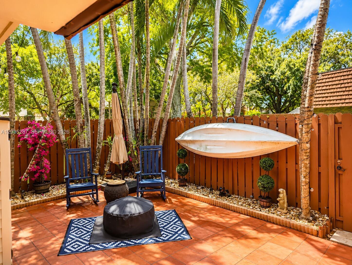 A patio features two blue rocking chairs, a fire pit, and a boat mounted on a fence — 2589 Garden # 2589, Hollywood FL 33026, HOLLYWOOD, FL