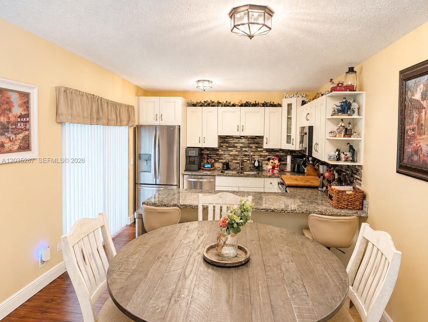 A kitchen with white cabinets, granite countertops, and a round wooden dining table — 2589 Garden # 2589, Hollywood FL 33026, HOLLYWOOD, FL