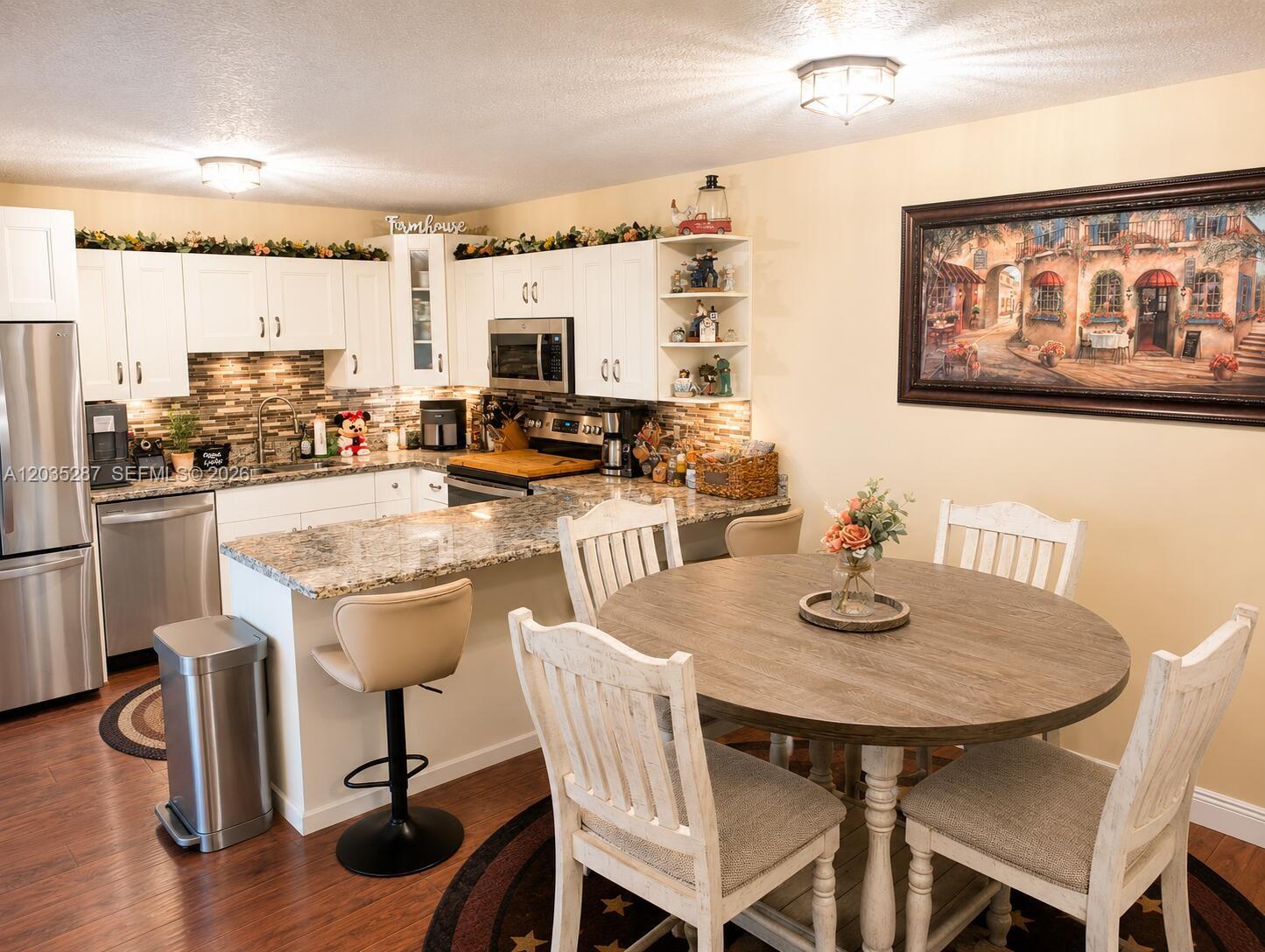 A kitchen with white cabinets, granite countertops, and a round wooden dining table — 2589 Garden # 2589, Hollywood FL 33026, HOLLYWOOD, FL