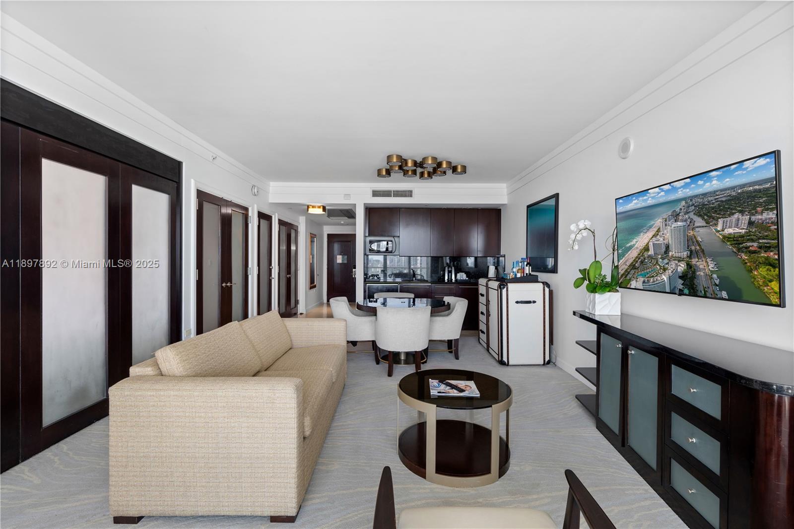 A living room with a sofa, coffee table, dining area, and wall-mounted television — 4391 Collins Ave # 1619, Miami Beach FL 33140, MIAMI BEACH, FL