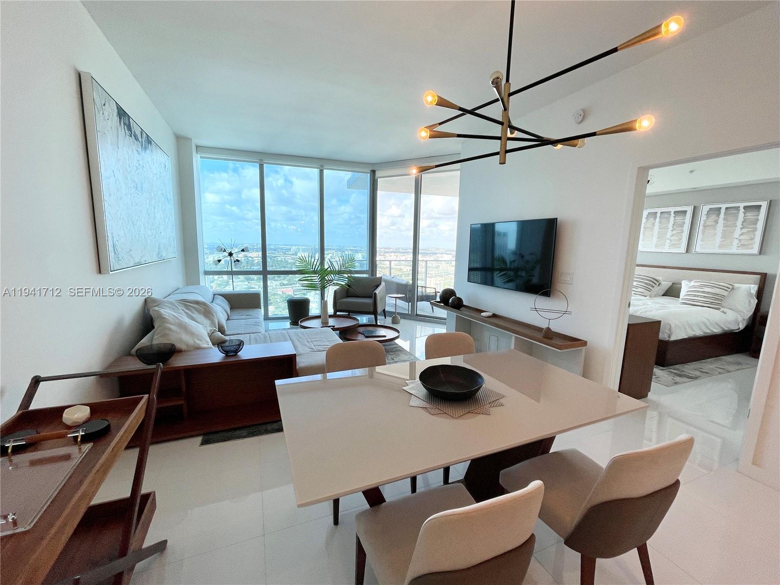 A modern living and dining area features floor-to-ceiling windows with a high-rise city view — 851 NE 1st Ave # 3606, Miami FL 33132, MIAMI, FL
