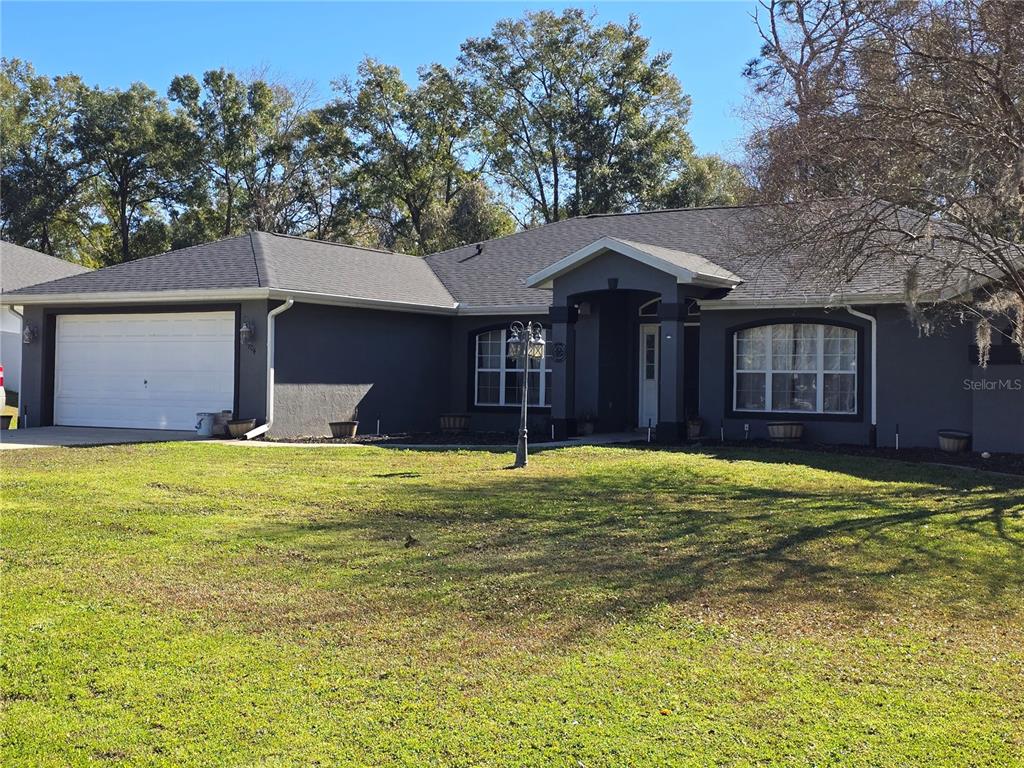 A dark gray single-story house with a white garage door and a front porch — 5904 SW 107TH STREET, OCALA, FL