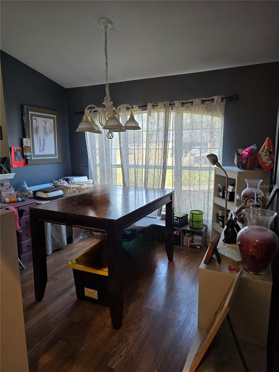 A dining room with a dark wood table, chandelier, and large window with sheer curtains — 5904 SW 107TH STREET, OCALA, FL