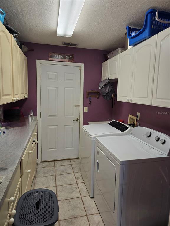 A laundry room features white cabinets, a white door, tile flooring, and a washer and dryer — 5904 SW 107TH STREET, OCALA, FL