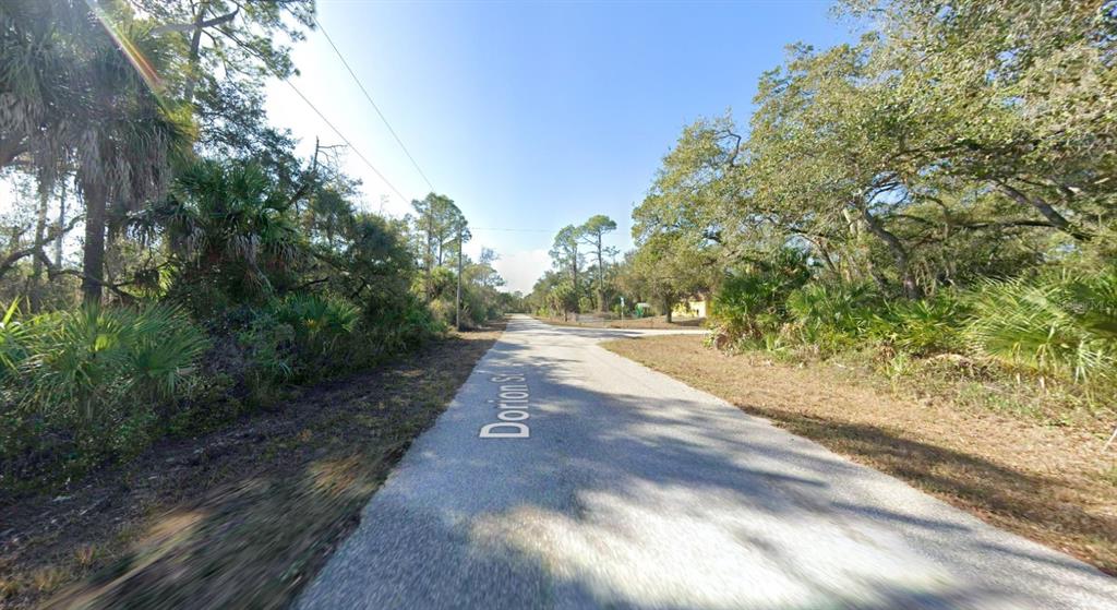 A paved road runs through a wooded area with dense vegetation on both sides — 2168 DORION STREET, PORT CHARLOTTE, FL