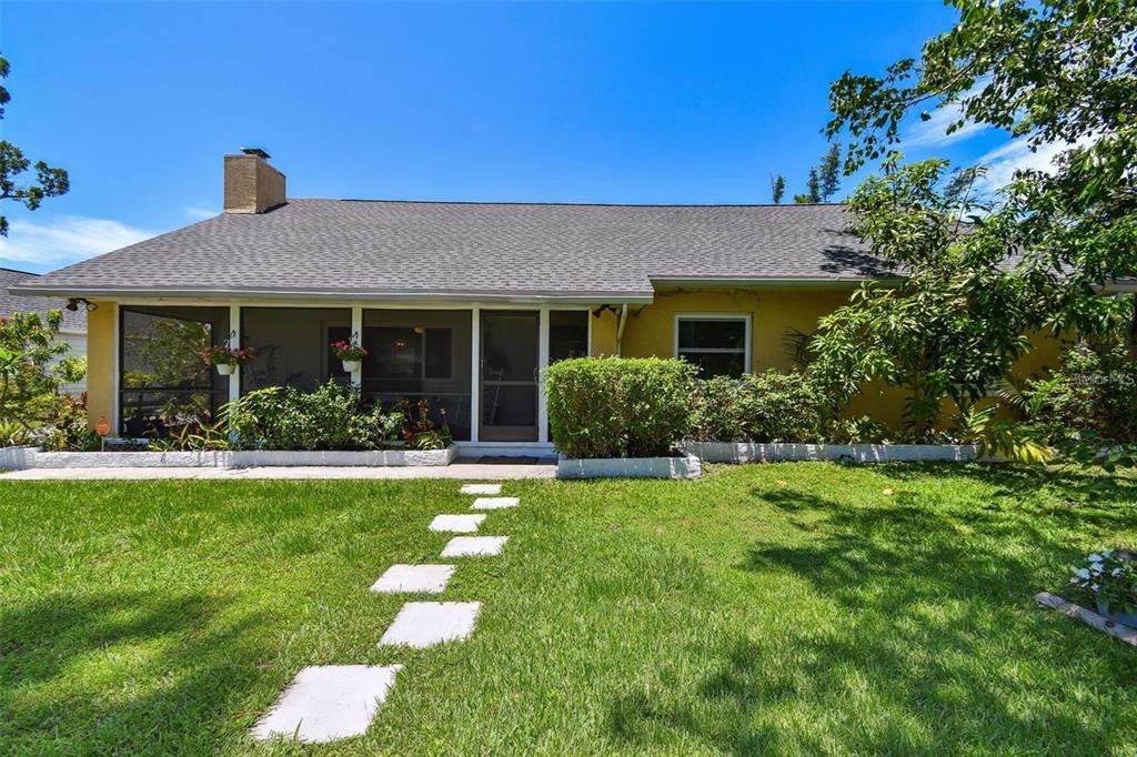 A yellow single-story house features a screened-in porch and a stone walkway across the lawn — 859 PATTERSON DRIVE, SARASOTA, FL