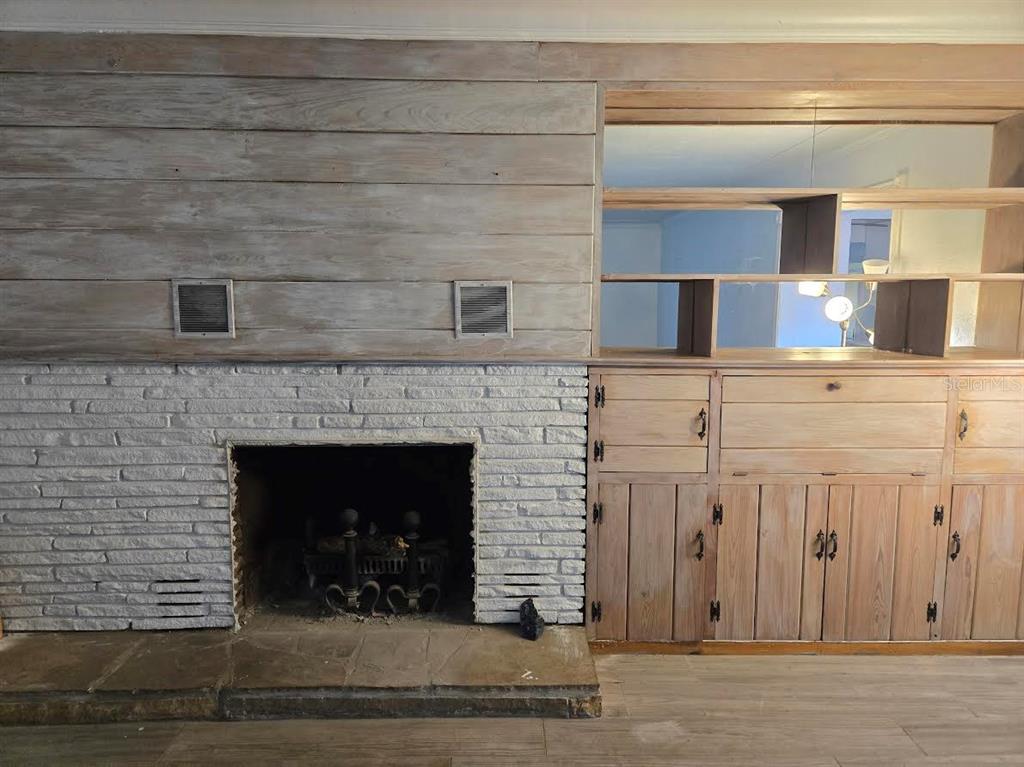 A room features a white brick fireplace, wood-paneled wall, and built-in wooden shelving and cabinets — 859 PATTERSON DRIVE, SARASOTA, FL