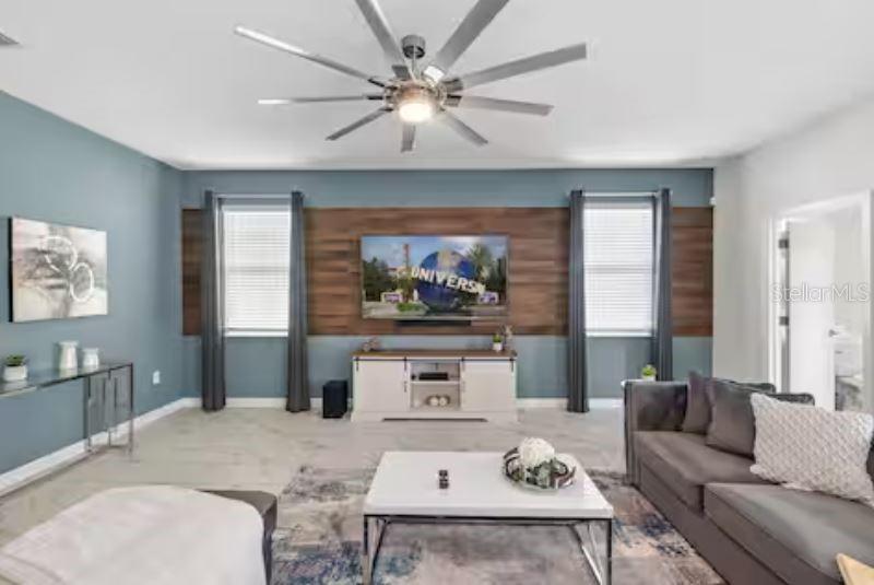 A living room features a wood-paneled accent wall, a large television, and a ceiling fan — 913 OCEAN COURSE AVENUE, DAVENPORT, FL