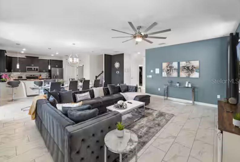 A spacious open-concept living room features a large gray sectional sofa and a modern kitchen — 913 OCEAN COURSE AVENUE, DAVENPORT, FL