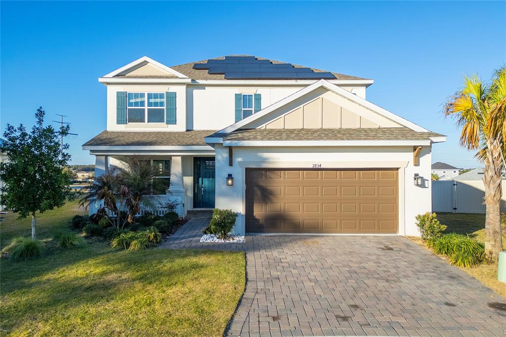 A two-story suburban house features a brown garage door, blue shutters, and rooftop solar panels — 2834 HIGH POINTE STREET, CLERMONT, FL