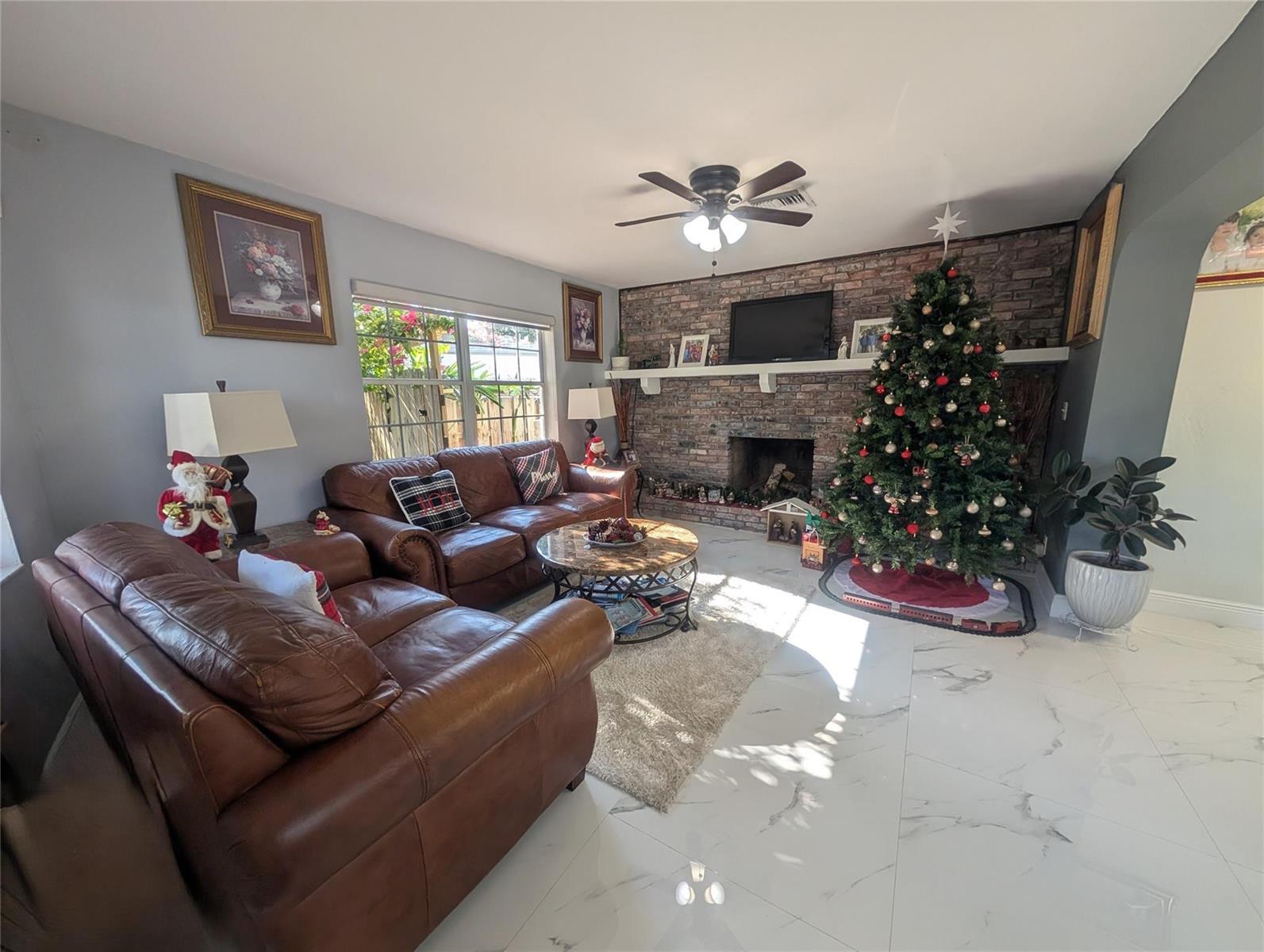 A living room features a brick fireplace, leather sofas, a Christmas tree, and tiled floors — 1313 NW 58th Avenue, Margate FL 33063, MARGATE, FL