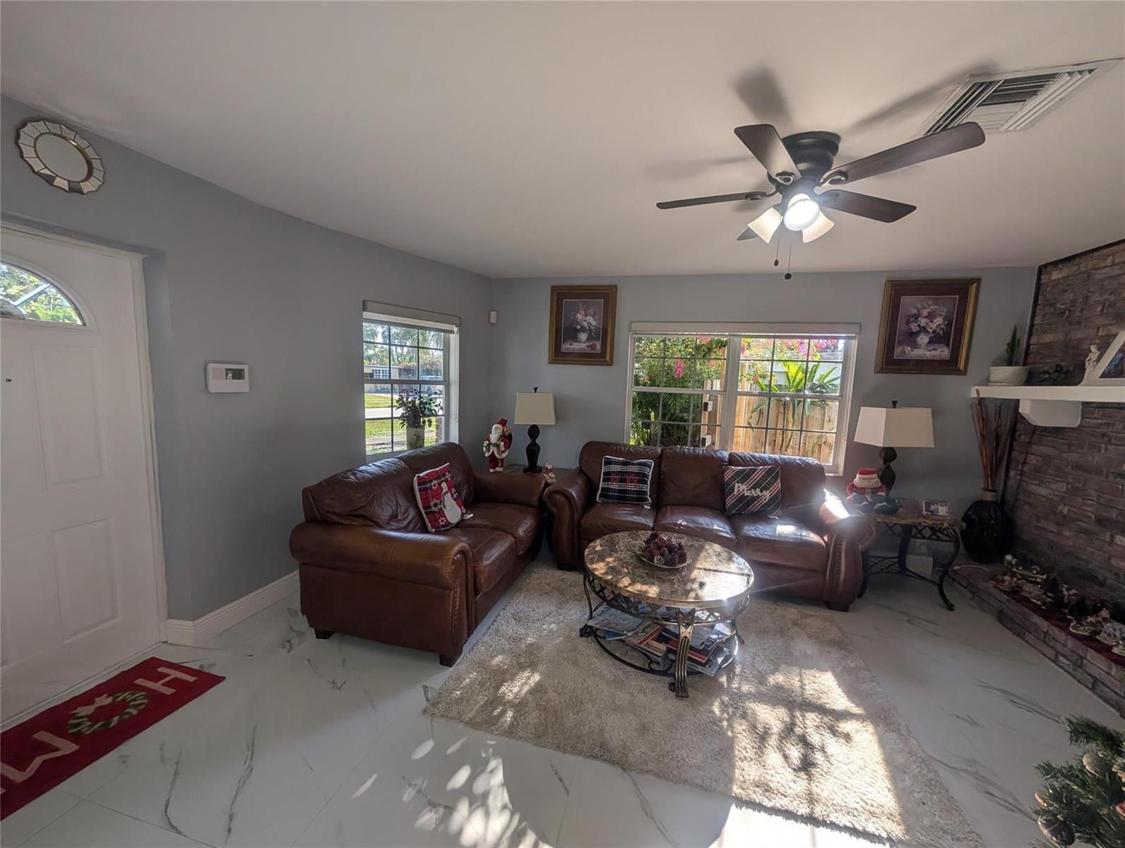 A living room features brown leather sofas, a stone fireplace, and white marble-look flooring — 1313 NW 58th Avenue, Margate FL 33063, MARGATE, FL