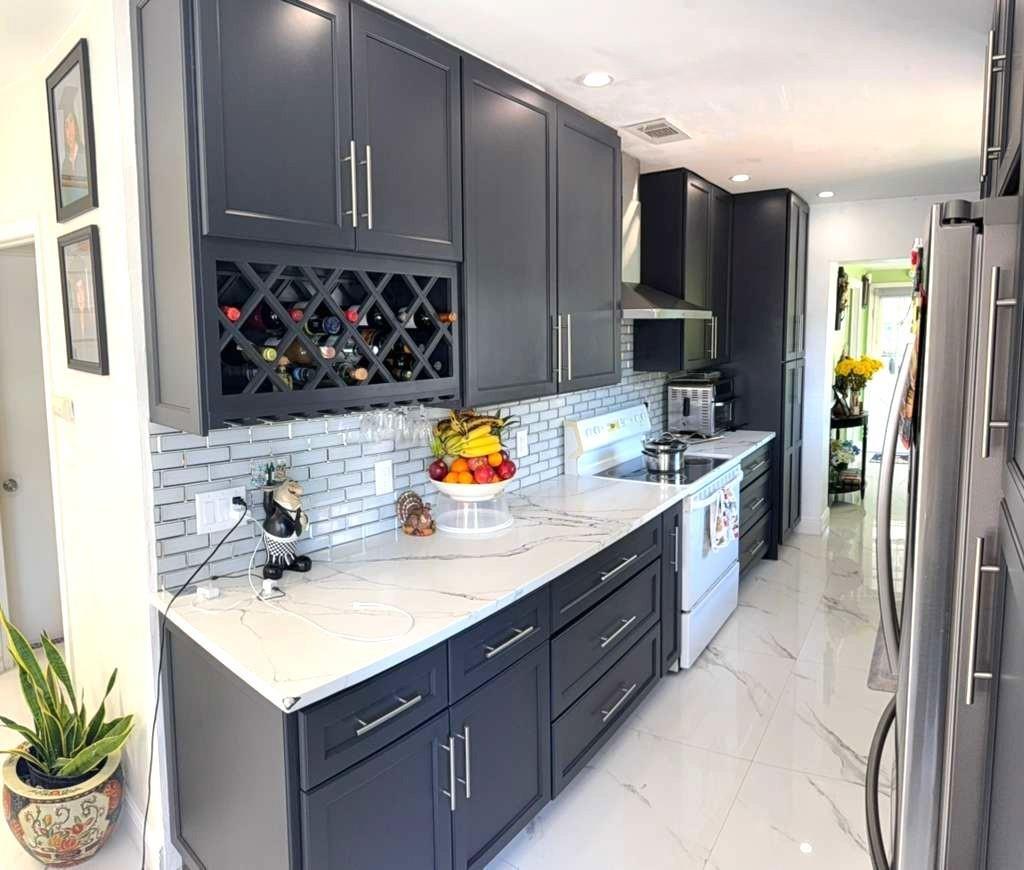 A modern kitchen features dark gray cabinets, white marble-look countertops, and a subway tile backsplash — 1313 NW 58th Avenue, Margate FL 33063, MARGATE, FL