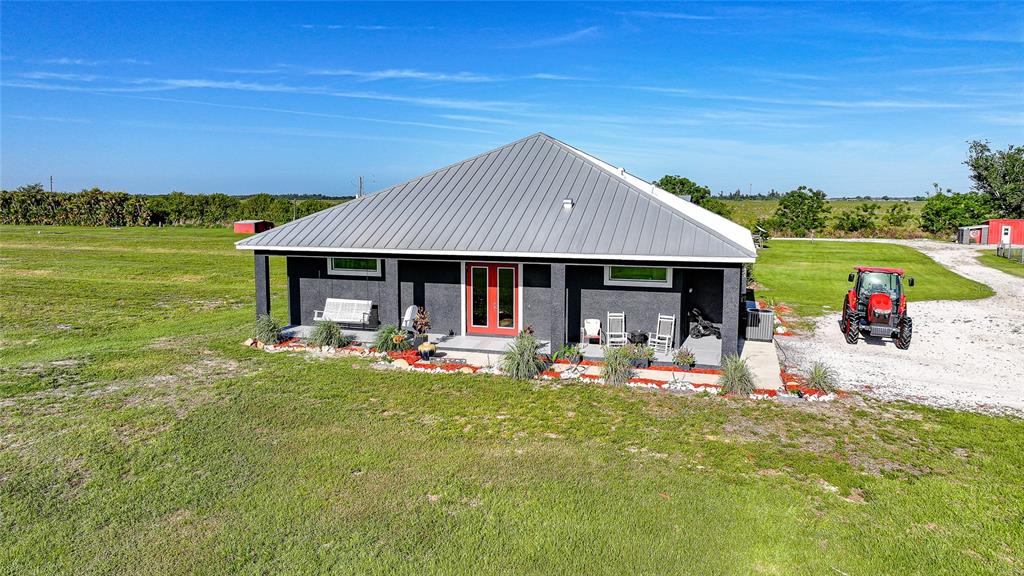 A single-story house with a metal roof and red front doors sits on a lawn — 9931 SE ENGLISH AVENUE, ARCADIA, FL
