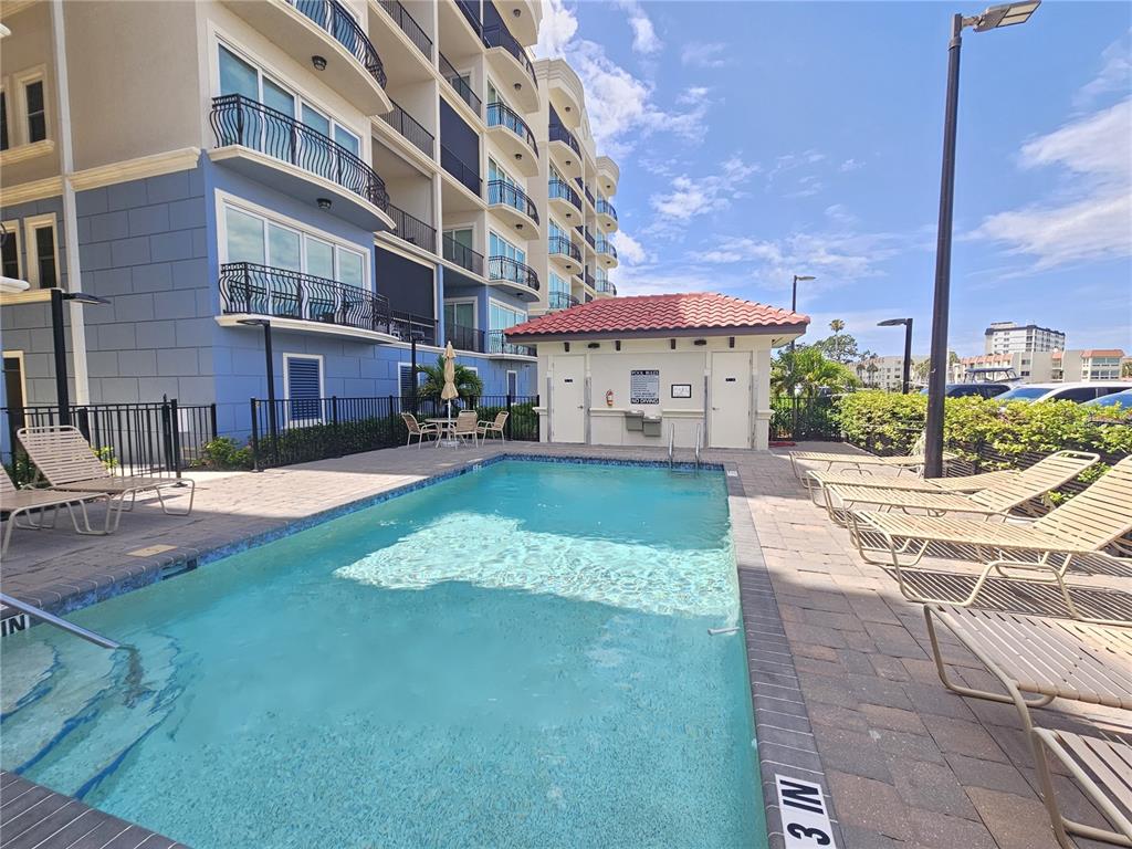 A rectangular swimming pool sits on a paved patio beside a multi-story building — 503 TAMIAMI TRAIL N UNIT 301, VENICE, FL