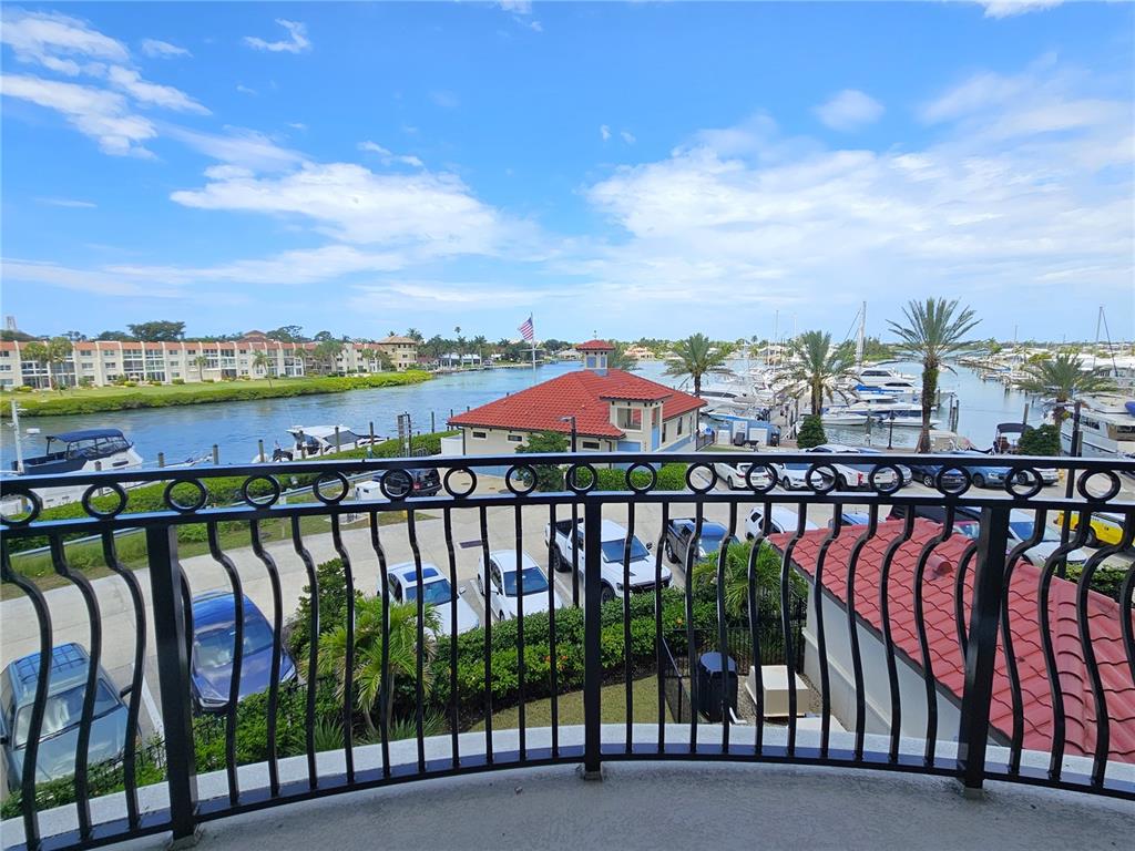 A balcony view overlooks a canal with boats, a red-roofed building, and parked cars — 503 TAMIAMI TRAIL N UNIT 301, VENICE, FL