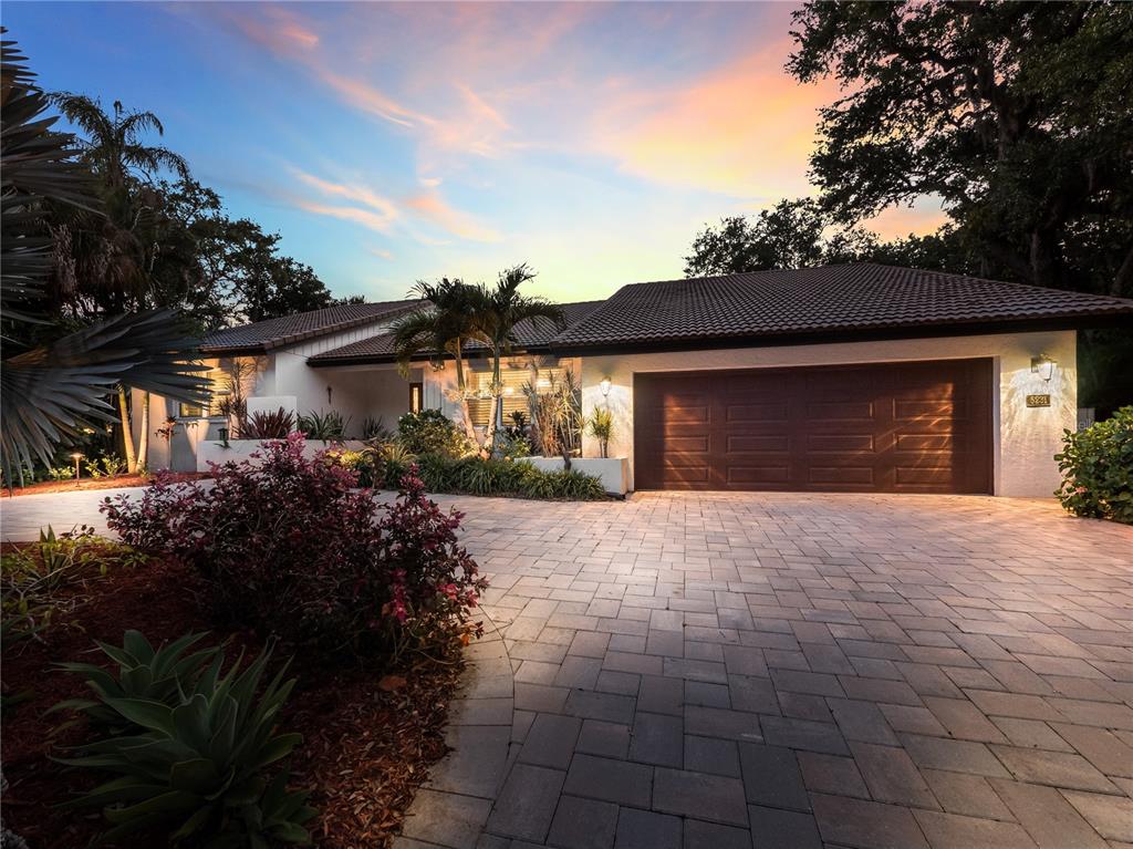 A single-story house with a brown garage door and a paved driveway at sunset — 5231 SIESTA COVE DRIVE, SARASOTA, FL