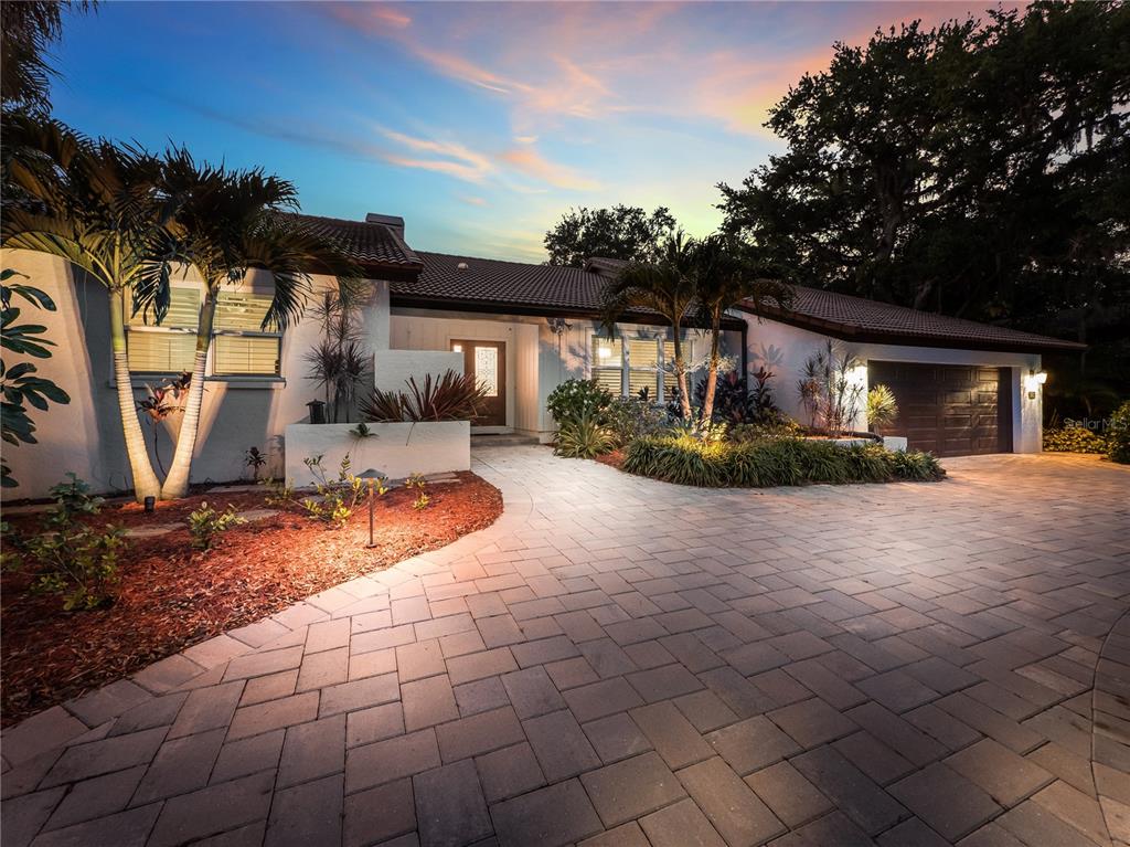 A single-story house with a paved driveway, palm trees, and a tiled roof at dusk — 5231 SIESTA COVE DRIVE, SARASOTA, FL