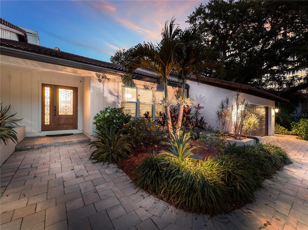 The exterior of a house features a paver walkway, a palm tree, and landscaping — 5231 SIESTA COVE DRIVE, SARASOTA, FL