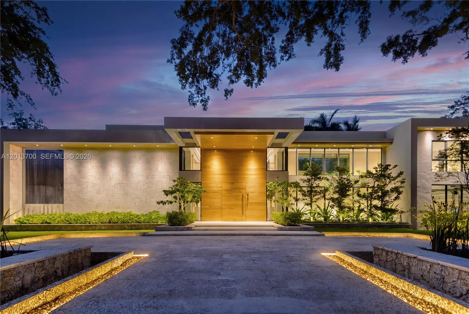 A modern two-story house features a large wooden front door and stone exterior walls — 6701 SW 101st St, Pinecrest FL 33156, PINECREST, FL