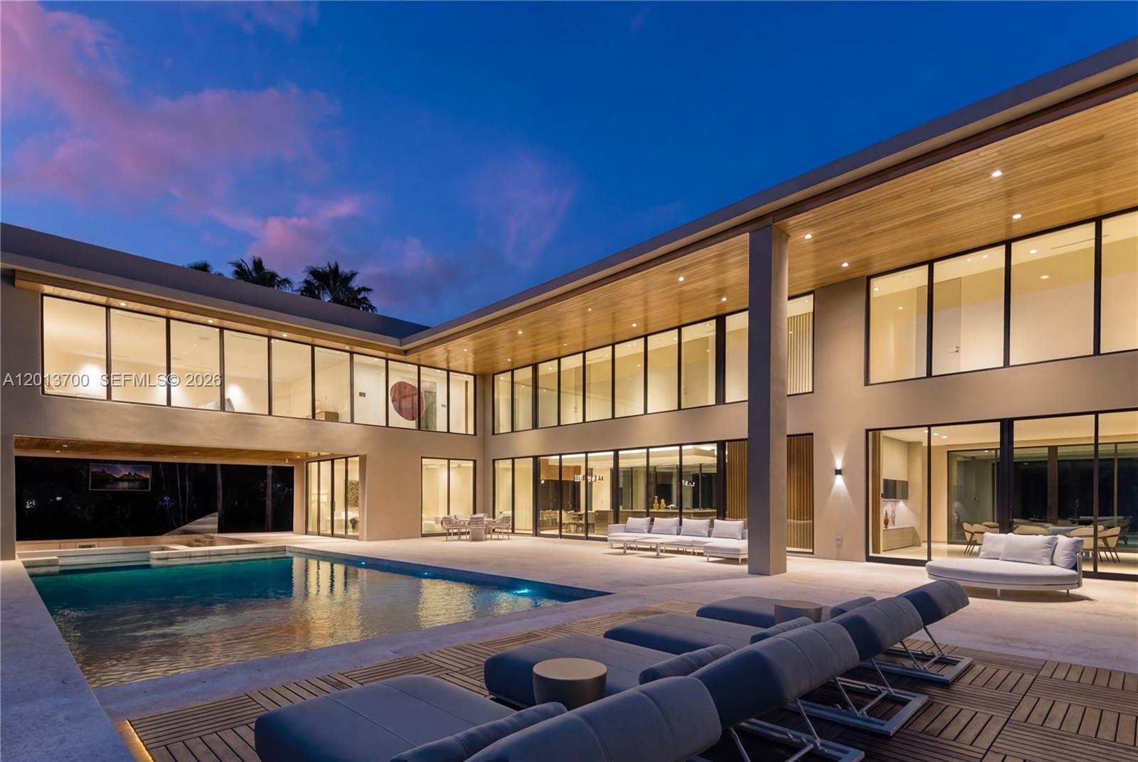 A modern two-story home features a large swimming pool, patio seating, and floor-to-ceiling windows — 6701 SW 101st St, Pinecrest FL 33156, PINECREST, FL