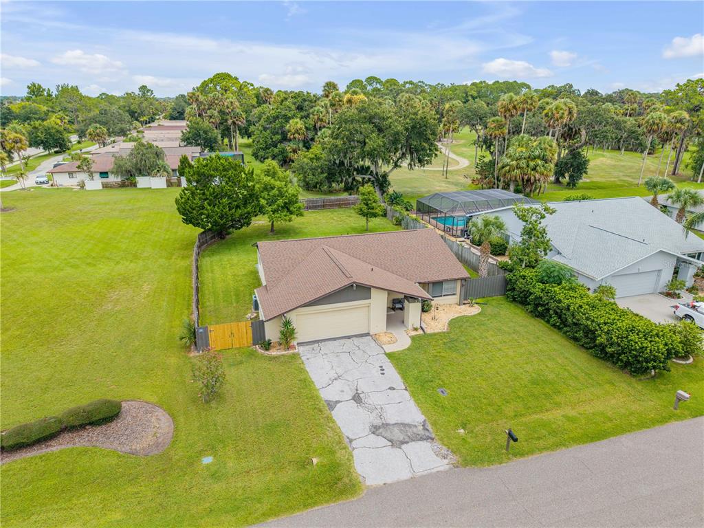 An aerial view of a single-story house with a cracked concrete driveway and fenced yard — 3 CASPER DRIVE, PALM COAST, FL