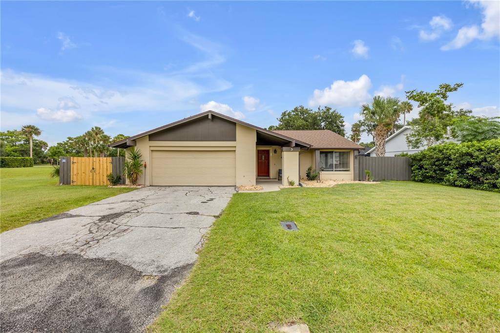 A single-story house with a beige exterior, a two-car garage, and a cracked concrete driveway — 3 CASPER DRIVE, PALM COAST, FL