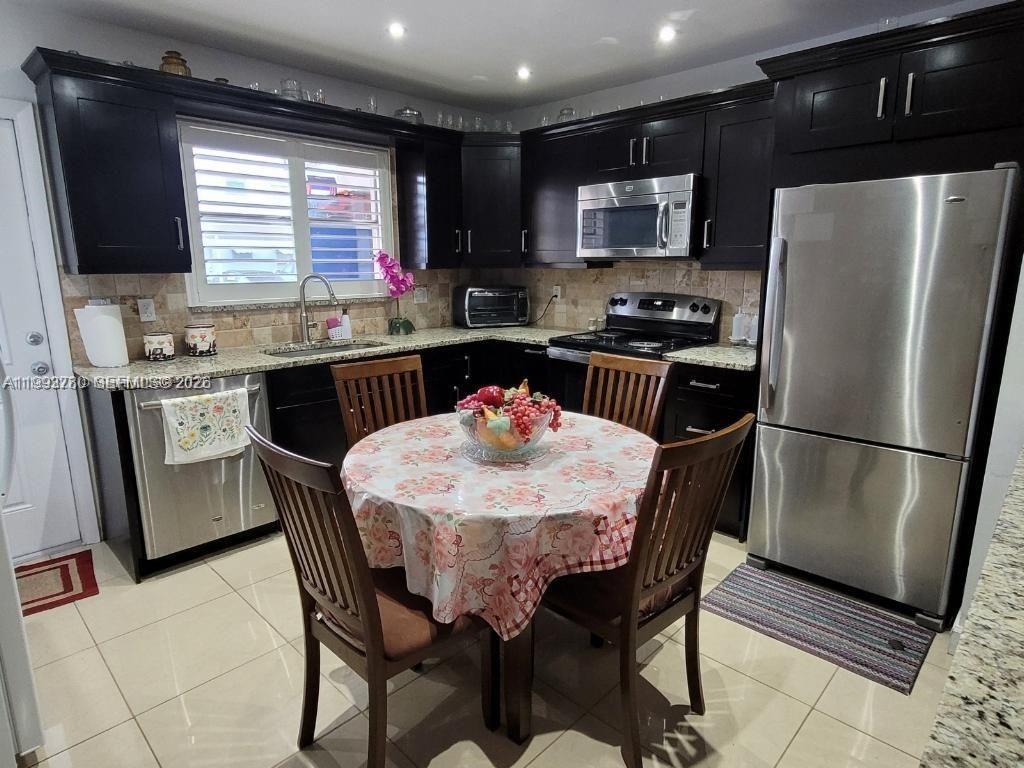 A kitchen features dark wood cabinets, stainless steel appliances, and a round dining table — 411 S Crescent Dr # 105, Hollywood FL 33021, HOLLYWOOD, FL