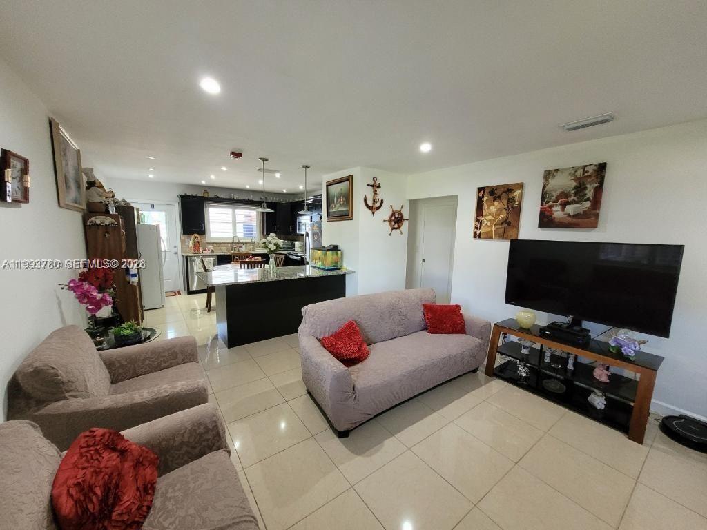 A living room with light-colored tile floors opens into a kitchen with dark cabinetry — 411 S Crescent Dr # 105, Hollywood FL 33021, HOLLYWOOD, FL