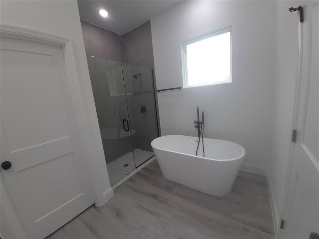 A bathroom features a freestanding white tub, a glass-enclosed shower, and light gray flooring — 16629 SW 21ST CIRCLE, OCALA, FL