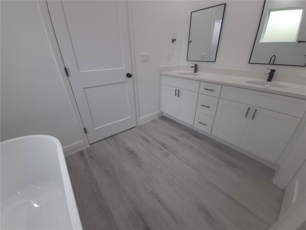 A modern bathroom features a double vanity, a freestanding tub, and light wood-look flooring — 16629 SW 21ST CIRCLE, OCALA, FL