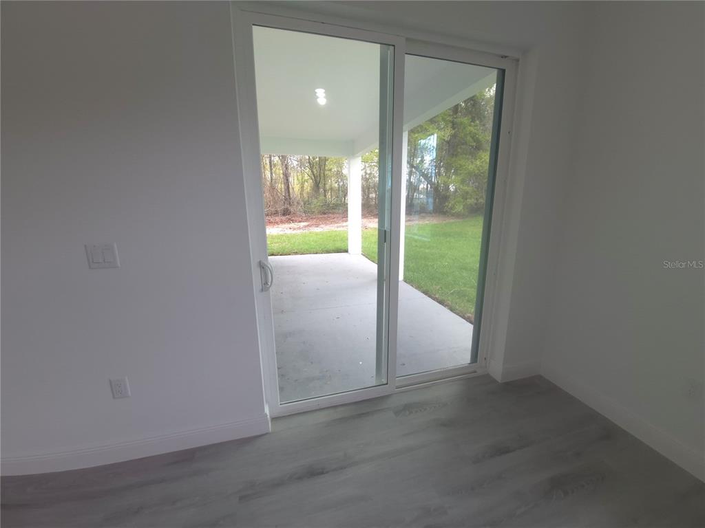 A room with light-colored wood-look flooring and a sliding glass door leading to a patio — 16629 SW 21ST CIRCLE, OCALA, FL