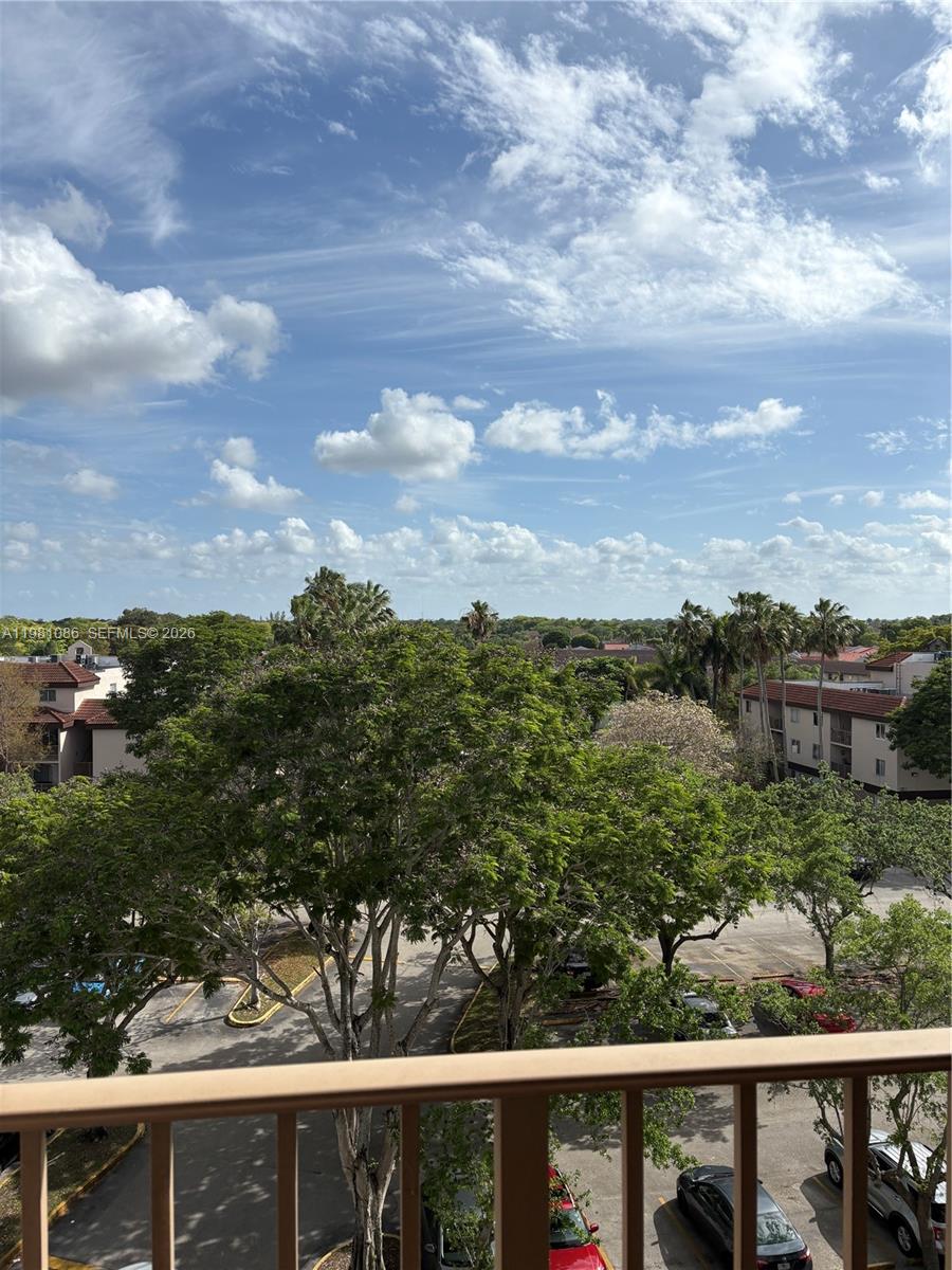 An elevated view from a balcony overlooks a parking lot, trees, and residential buildings — 15231 SW 80th St # 615, Miami FL 33193, MIAMI, FL