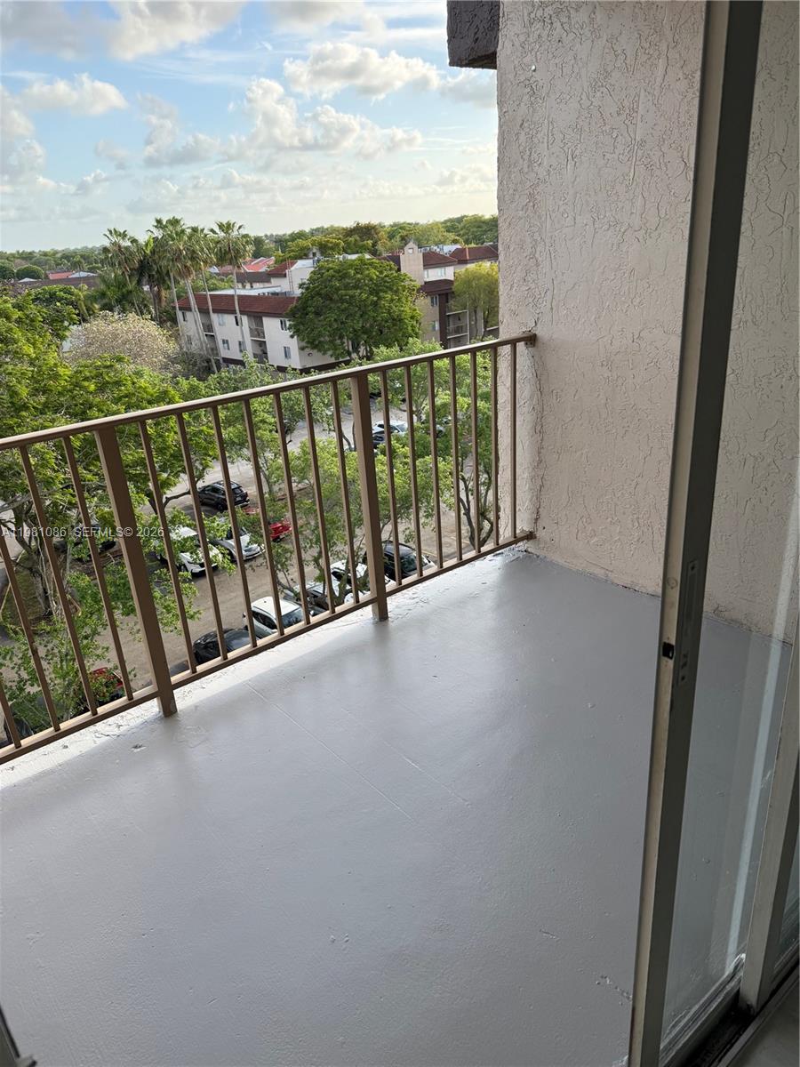 A balcony with a gray painted floor and metal railing overlooks a parking lot — 15231 SW 80th St # 615, Miami FL 33193, MIAMI, FL