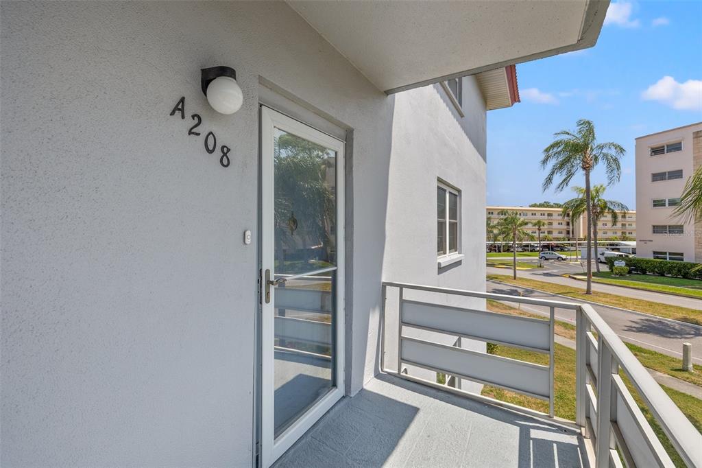 An exterior balcony features a white door labeled A208 and a metal railing — 5660 80TH STREET N UNIT A208, ST PETERSBURG, FL