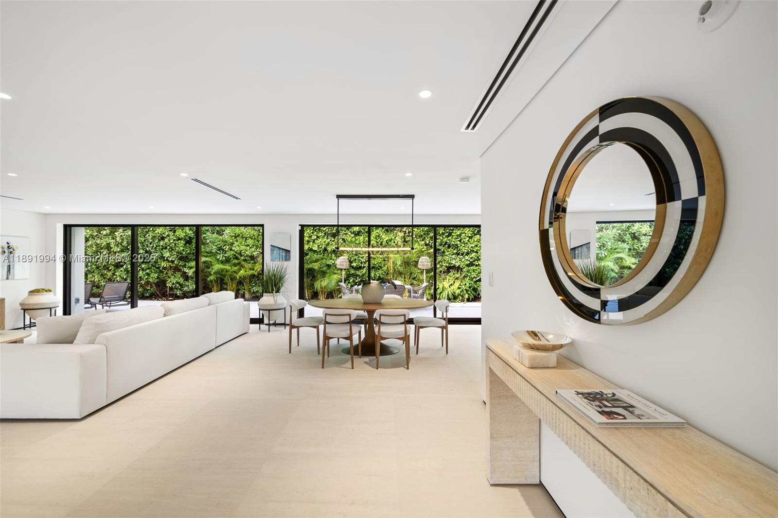 A modern living and dining area features white furniture, a round table, and large windows — 222 E Rivo Alto Dr, Miami Beach FL 33139, MIAMI BEACH, FL